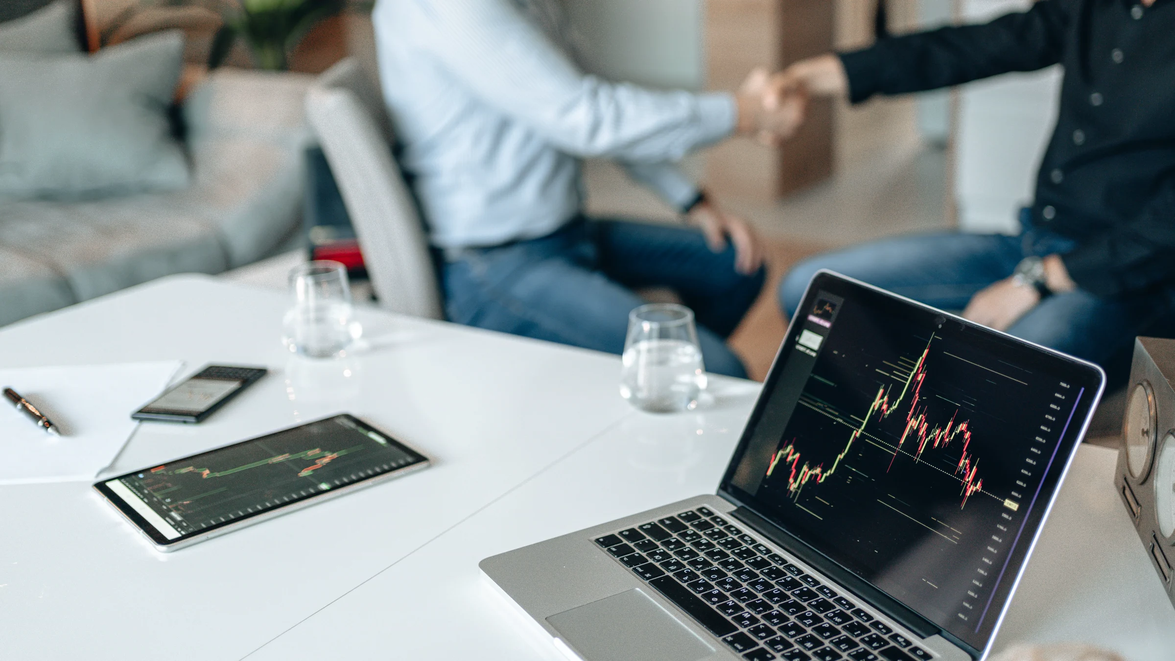 A business discussion with market data displayed on a laptop and tablet.